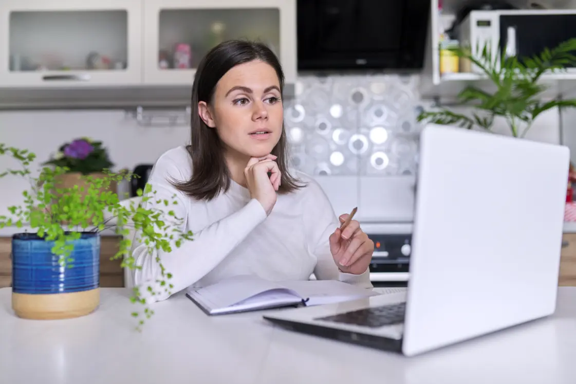 Lady sat at the table on her laptop during an online therapy session.