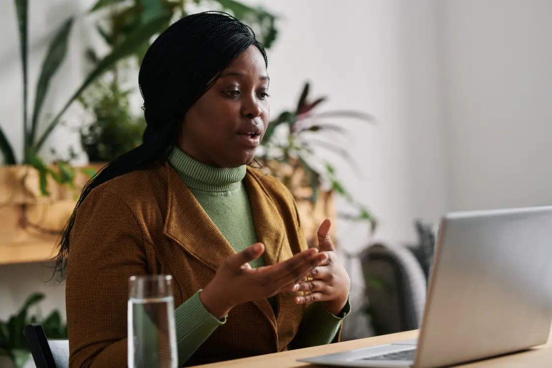 Lady sat acing her laptop talking to the screen during an online therapy session