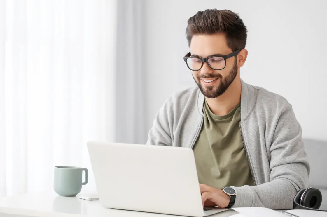 Man sat at the table on his laptop during an online therapy session